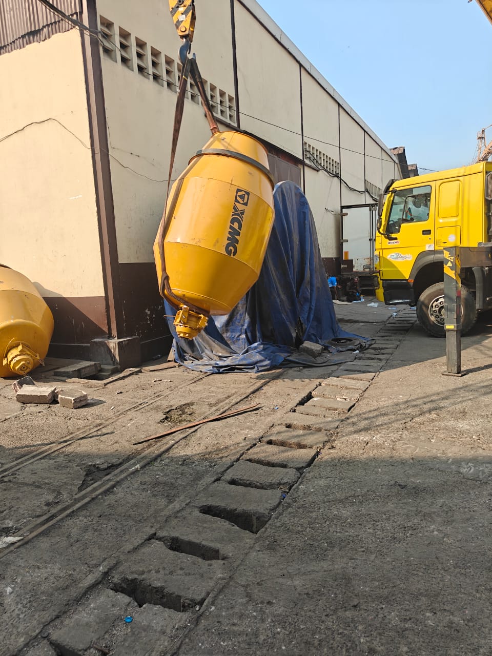 Une cuve de malaxage est suspendue à une grue pendant une opération de manutention.